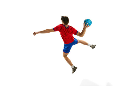 Back view. Throwing ball in a jump. Young man, professional handball player in red uniform playing, training isolated over white studio background. Concept of sport, action, motion, sportive lifestyle