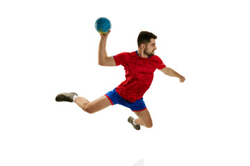 In a jump. Dynamics. Young man, professional handball player in red uniform playing, training isolated over white studio background. Concept of sport, action, motion, championship, sportive lifestyle