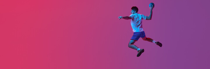 Throwing ball. Young man, professional handball player playing isolated over gradient pink background in neon light. Sport, championship, sportive lifestyle concept. Banner, flyer. Copy space for ad