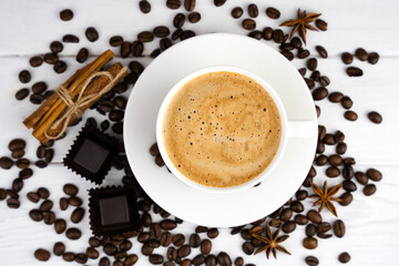 Cup of coffee, chocolate candies, scattered coffee beans and spices on a white background. Preparation of natural coffee. Close-up. Top view. Selective focus.