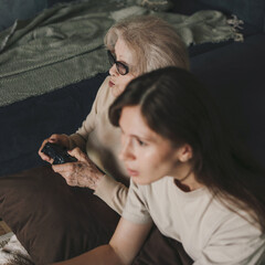 Happy adult woman and her senior mother playing video games together at home. Family activities. Family home leisure. Happy family.