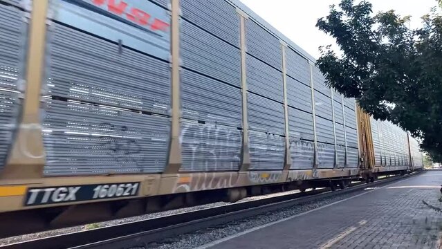 Large cargo train flying through a small town with graffiti painted on its side.