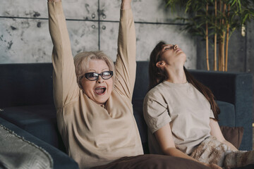 Excited gamer senior woman playing video games, she is holding a controller making winnner gesture....