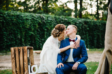 Bride and groom kissing after wedding ceremony. Newlyweds are photographed on a wooden photo zone. Wooden decor.