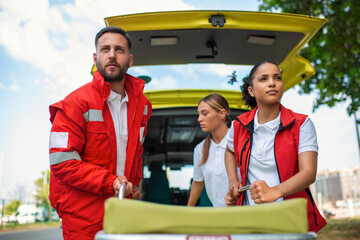 paramedics with a stretcher near an ambulance. Paramedics in uniform taking stretcher out the...