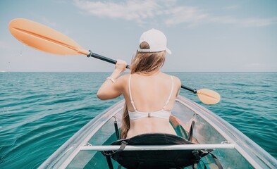 Woman in kayak back view. Happy young woman with long hair floating in transparent kayak on the...