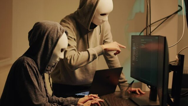 Mysterious spies working on phishing and cryptojacking, trying to break into government server and steal valuable data. Team of hackers with anonymous masks hacking online system.