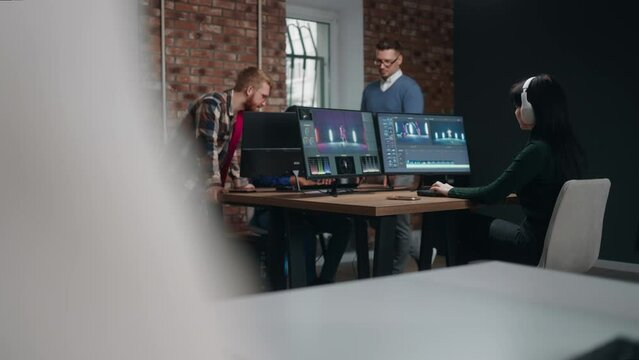 creative team of filmmakers and editors working in studio, woman making montage of video by computer