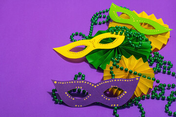 Festive Mardi Gras masquerade purple background. Fat Tuesday carnival, masks, beads, traditional decor