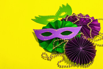 Festive Mardi Gras masquerade yellow background. Fat Tuesday carnival, masks, beads, traditional decor