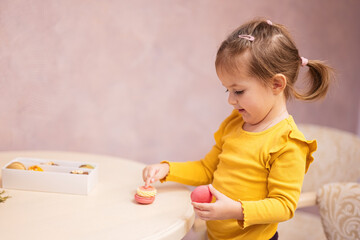 Baby girl eat delicious tasty sweet color macaron.