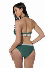 A lady in a two-piece gray and green swimsuit with silver ribbons composed of low-rise bikinis and a bra with a neck strap. The woman is standing with her back to the camera on a white background.