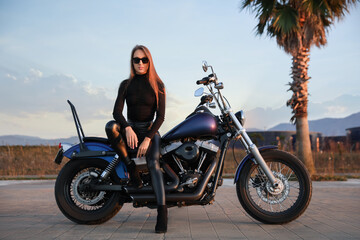Fototapeta na wymiar Beautiful young woman sitting on motorcycle outdoors