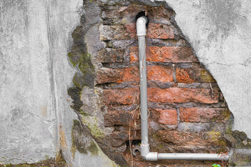 Broken concrete and brick wall with water pipes exposed