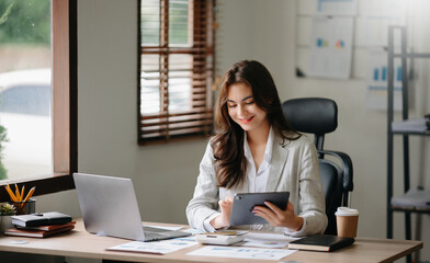 Asian businesswoman working in the office with working notepad, tablet and laptop documents