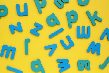 Pile of jumbled messy letters pattern on yellow background. Latin alphabet block colored letters. Dyslexia awareness confusion brain thinking psychology problem. English learning concept. Close up