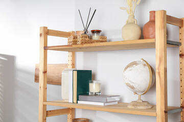 Wooden shelving unit with home decor near light wall