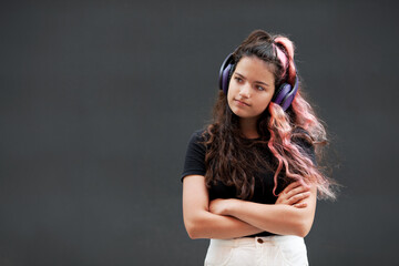 Young Girl with colored long pink hair listen to music with headphones isolated on dark gray background