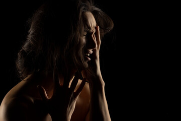 Silhouette of young unhappy crying woman on black background