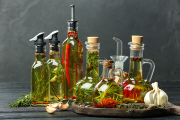 Cooking oil with different spices and herbs in bottles on grey wooden table