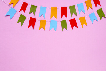 Obraz premium Colorful bunting flags on pink background, flat lay. Space for text