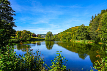 Green nature at a pond near Willingen. View of the lake with the surrounding landscape in the...