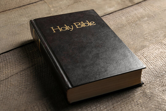 One hardcover Bible on wooden table, closeup