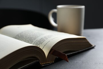Fototapeta premium Open hardcover Bible on black table indoors, closeup. Religious book