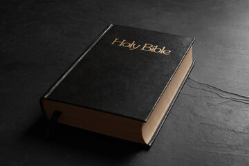 Hardcover Bible on black table, closeup. Religious book