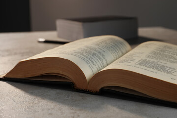 Obraz premium Closeup view of open hardcover Bible on grey table indoors. Religious book