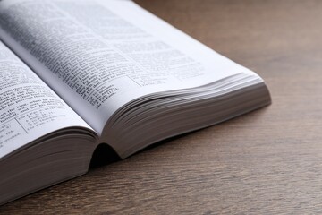 Open Bible on wooden table, closeup. Religious book