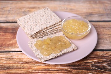 Tasty crispbreads with jam on wooden table, closeup