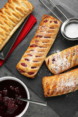 Fresh tasty puff pastry with sugar powder served on grey table, flat lay
