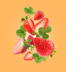 Delicious sweet strawberries and green leaves falling on orange background