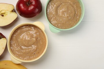 Bowls with puree and fruits on white wooden table, flat lay and space for text. Baby food