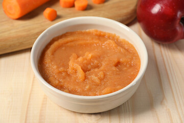 Healthy baby food. Bowl with delicious carrot puree on wooden table, closeup