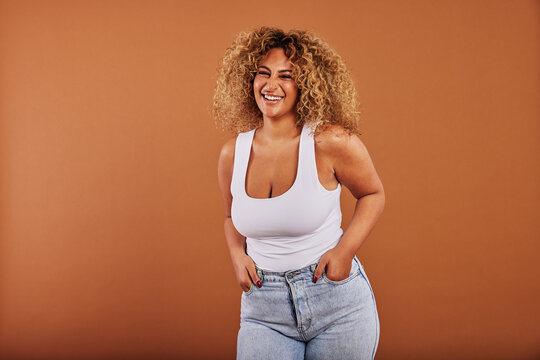 Young woman wearing jeans smiling against an orange background - Powered by Adobe