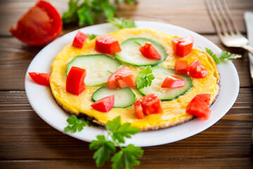 Fried omelet with zucchini, tomatoes, herbs in a plate