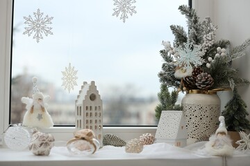 Many beautiful Christmas decorations on window sill indoors