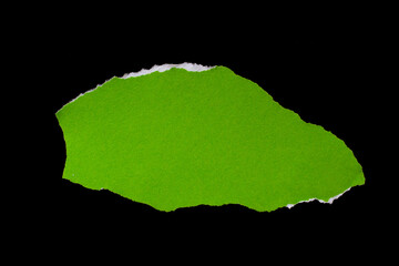 Green torn paper piece isolated on black background