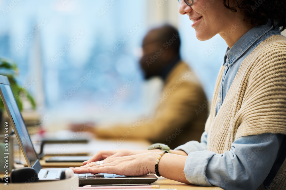 Aufkleber close-up of young female manager typing by desk while sitting in front of laptop screen against male