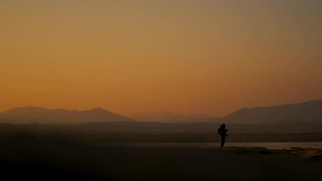 Silhouette photographer tourist hiker and lake garda in sirmione, italy. Sunset golden warm light, twilight shadow of a person in nature, isolated alone