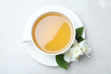 Obraz na płótnie Canvas Cup of tea and fresh jasmine flowers on light grey marble table, top view