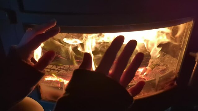 Women's hands near the burning fireplace in the house. Warming up near the fire.