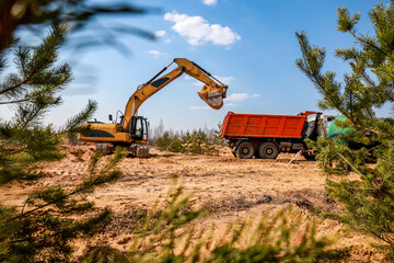 excavator loads loading dumper trucks at a construction site. Construction site industrial background