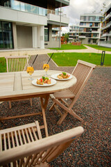 Group of friends sitting on a summer terrace with cocktails and wine in their hands and snacks on the table