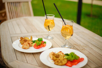Closeup of a cocktail with orange slices on the table with snacks and decorations on the background