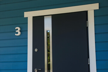 Number three on blue wooden house near stylish door outdoors