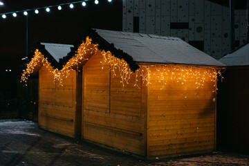 Christmas fair stalls decorated with beautiful festive lights and pine garland outdoors