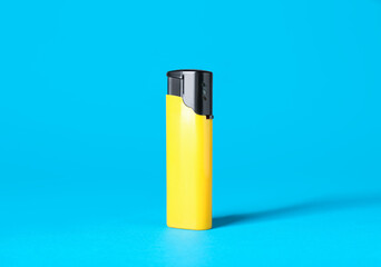 Yellow plastic cigarette lighter on light blue background